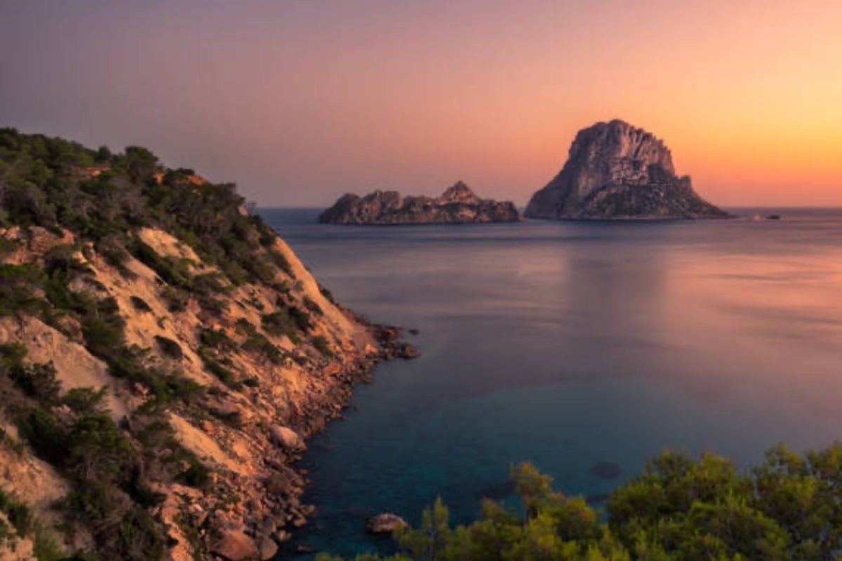 A vista looking out over the sea between rocks at sunset