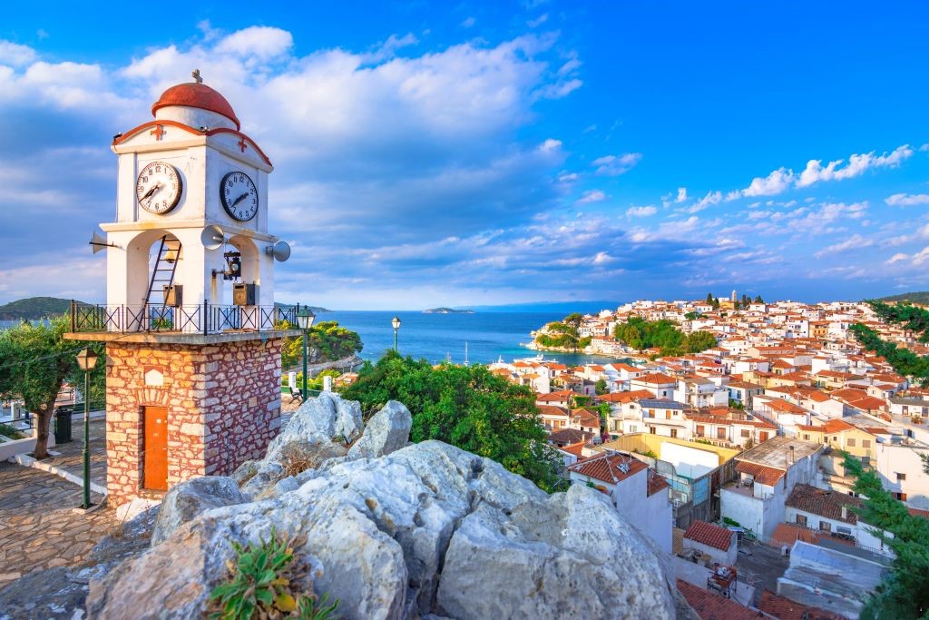 A view of clocktower with a classic Greek village backdrop